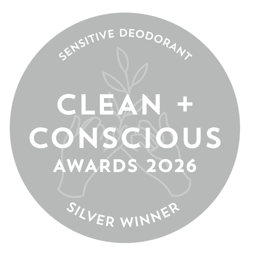 A circular gray badge with white text reading 'SENSITIVE DEODORANT', 'CLEAN + CONSCIOUS AWARDS 2026', and 'SILVER WINNER', with a faint botanical and hands illustration in the center.